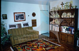 A living room decorated with embroidered pillows, a woven carpet, pottery and woodcraft